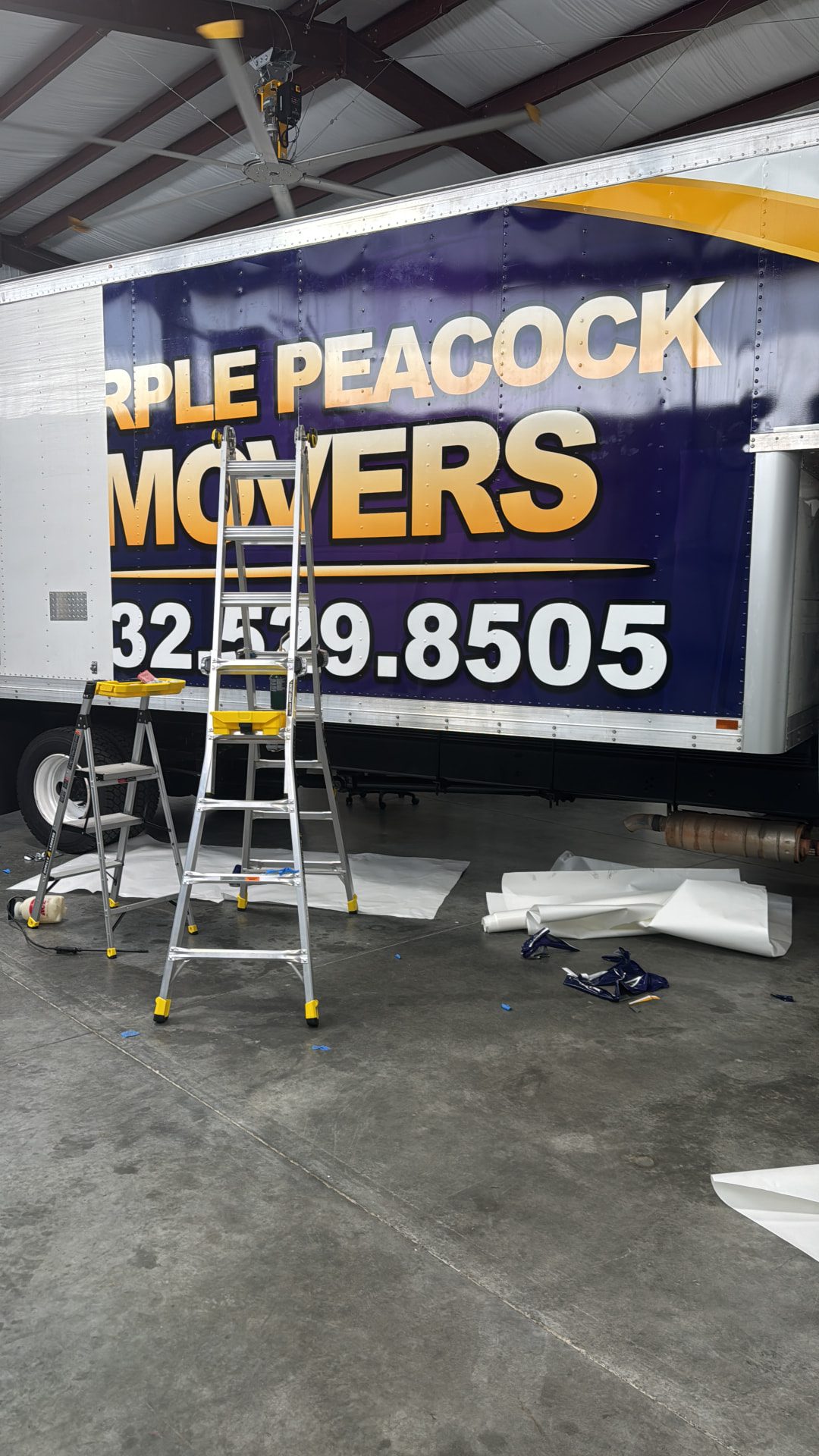 Installers applying a wrap to a box truck on ladders